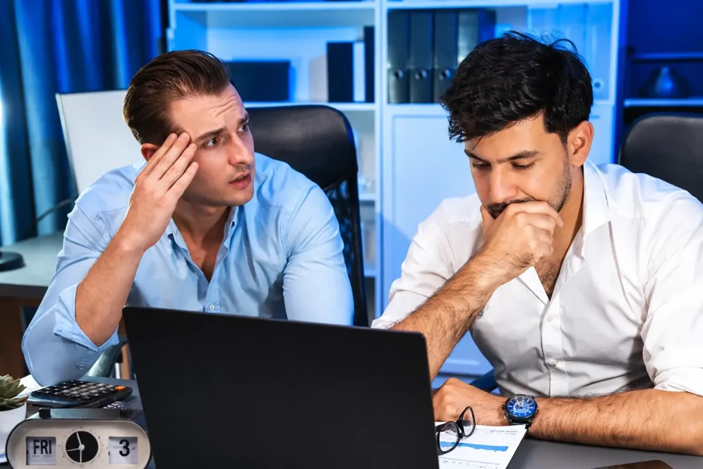 Two concerned men reviewing a website on a laptop